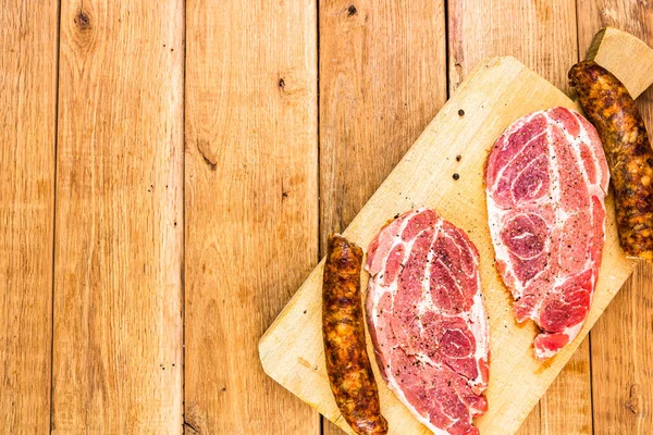 Pork chops with condiments and smoked sausage on a wooden cuttin — Stock Photo, Image