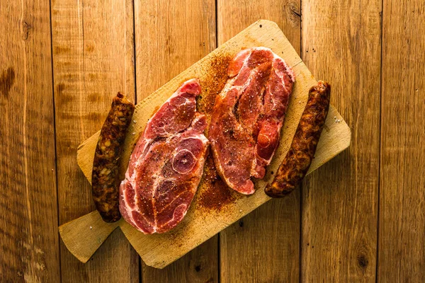 Pork chops with condiments and smoked sausage on a wooden cuttin — Stock Photo, Image