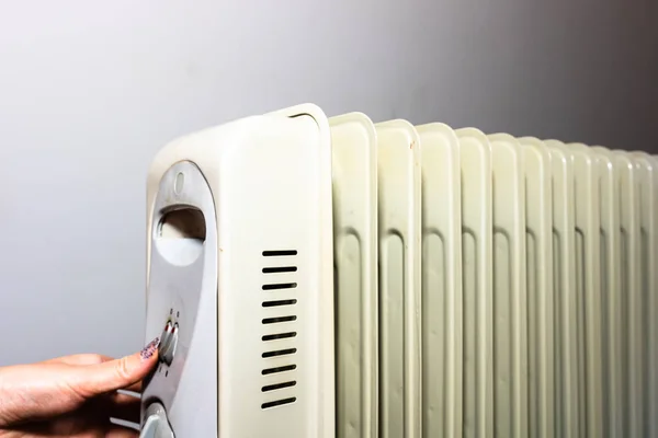 Mãos ligadas ao aquecedor do radiador de óleo sobre fundo branco — Fotografia de Stock