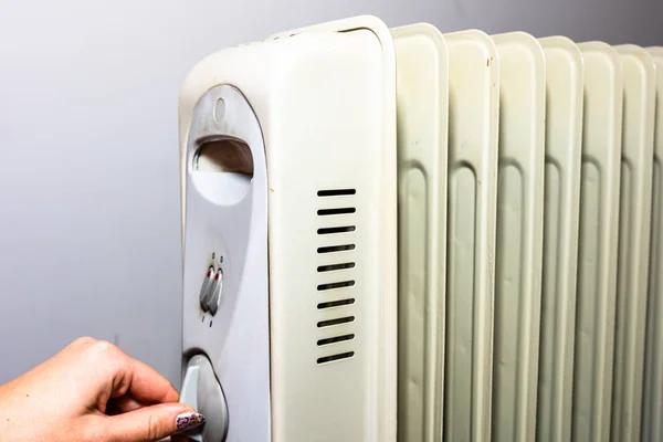 Mains allumant le radiateur à huile sur fond blanc — Photo