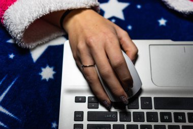 Dizüstü bilgisayarın üzerinde beyaz bir fare kullanan kadın elinin ayrıntıları.