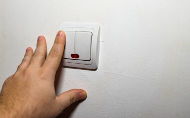 El, duvar lambasının düğmesini açıp kapatıyor. Işığı kapat.