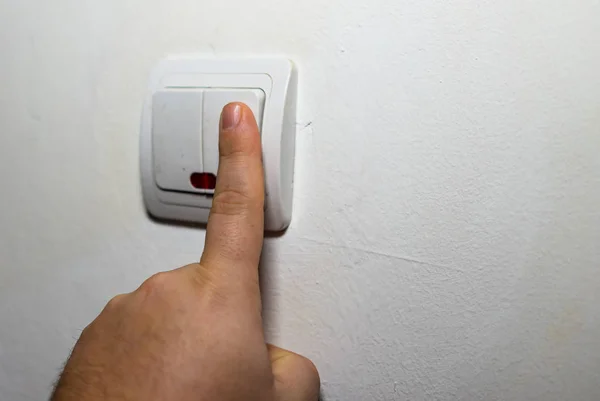 Hand turning the wall light switch on/off. Light switch close up