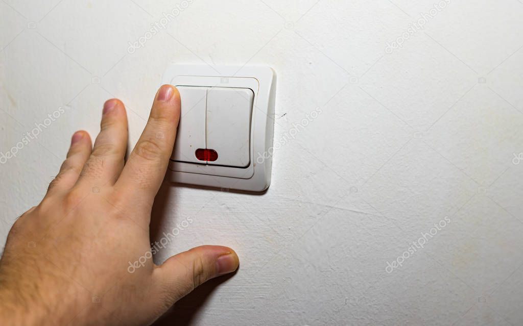 Hand turning the wall light switch on/off. Light switch close up