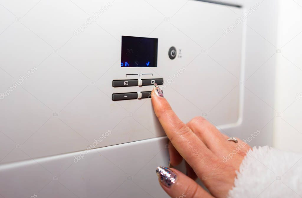 Control panel of central heating. Hand adjusting the room temper