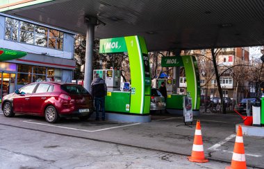 İnsanlar Mol benzin istasyonunda arabalarının deposunu dolduruyorlar.