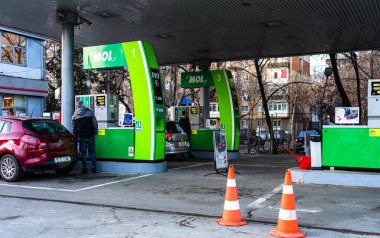 İnsanlar Mol benzin istasyonunda arabalarının deposunu dolduruyorlar.