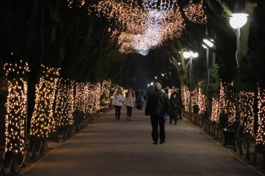 Buch 'taki Cismigiu Park' ın aydınlık sokaklarında yürüyen insanlar.