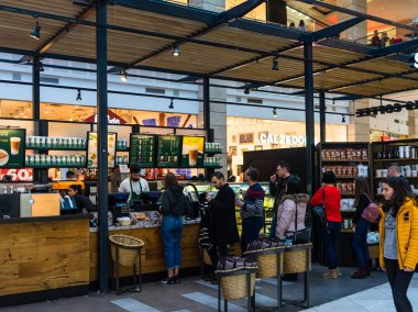 İnsanlar oturuyor, sırada bekliyor ve Starbucks 'ta çalışıyor. 