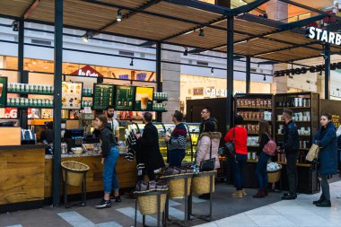 İnsanlar oturuyor, sırada bekliyor ve Starbucks 'ta çalışıyor. 