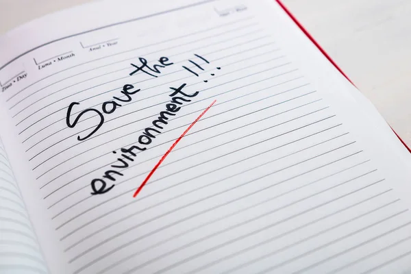 Guardar el medio ambiente, texto de escritura a mano en la página de agenda de la oficina . — Foto de Stock