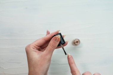 Manikür yapan kadın elleri, altın renginde oje.