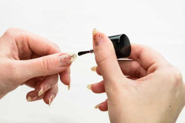 Female hands doing manicure, nail polish in gold glitter color o — Stock Photo, Image