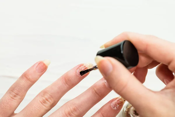 Female hands doing manicure, nail polish in gold glitter color o — Stock Photo, Image