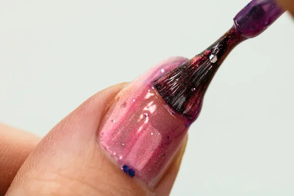 Mãos femininas fazendo manicure, esmalte de unhas em cor dourada brilhante o — Fotografia de Stock