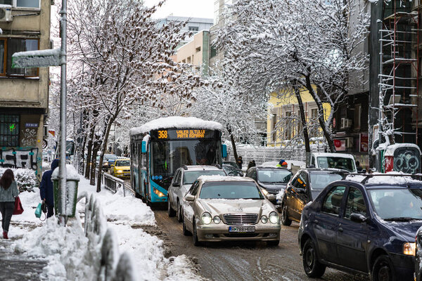 Snow on cars in the morning. Winter season and icy cars on the road in morning rush hour traffic of Bucharest, Romania, 2020