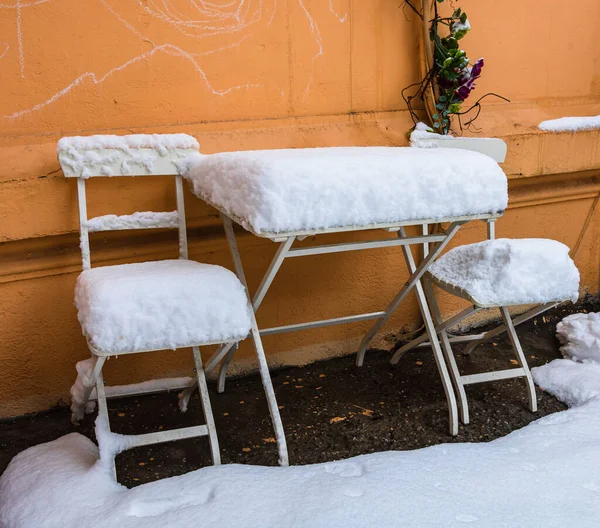 Perfectly shaped snow on table and chairs, covered with snow.