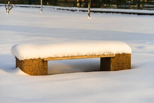 Snow-covered bench in the park. Park bench covered with snow fro