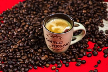 Bir fincan kahve, kırmızı arka planda kavrulmuş kahve çekirdekleri, üst manzara.,