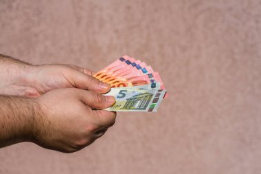 Avro parasını gösteren ve bahşiş, maaş gibi para veren ya da alan el ele tutuşmalar. 5 ve 10 EURO banknotları EUR izole edilmiş. Zengin iş adamları kavramı, para biriktirmek ya da harcamak.