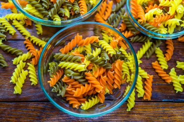 Çiğ makarna, pişmemiş üç renkli fusilli, makarna şeklinde. Renkli fusilli makarnaya odaklan. Fusilli makarna kasede.