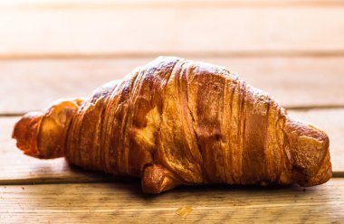 Tahta masadaki taze kruvasanın ayrıntıları. Yemek ve kahvaltı konsepti. Üst görünüm ve kopyalama alanı