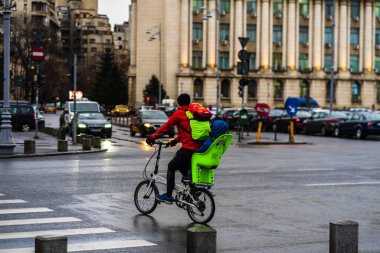 Yağmurlu bir günde, Romanya 'nın başkenti Bükreş' in ana bulvarında bisikletli bir adam karşıdan karşıya geçiyor.