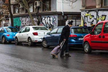 Yaşlı adam yağmurlu bir günde Bükreş 'in ana bulvarı Romanya 2020' de karşıdan karşıya geçiyor.