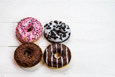 Beyaz ahşap masada renkli çörekler. Şekerli, şekerli, şekerli, şekerli, şekerli. Kopyalama alanı olan üst görünüm