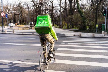 Uber Eats logosuna sahip bisikletli genç adam, 2020 Bükreş, Romanya 'da yiyecek dağıtıyor.