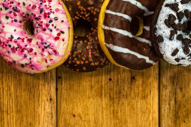 Masada fotokopi alanı olan renkli çörekler. İzole edilmiş donutların üst görünümü.