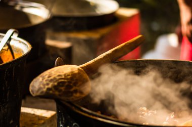 Ahşap kaşık buhar kazanı üzerinde izole edilmiş ve bir yemek festivalinde açık ateşte yanıyor..