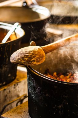 Ahşap kaşık buhar kazanı üzerinde izole edilmiş ve bir yemek festivalinde açık ateşte yanıyor..