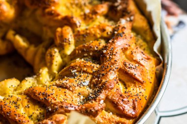 Örülmüş poğaça üzerine tuz ve haşhaş tohumlarının detaylarına odaklanmış seçici bir fotoğrafla kapat..