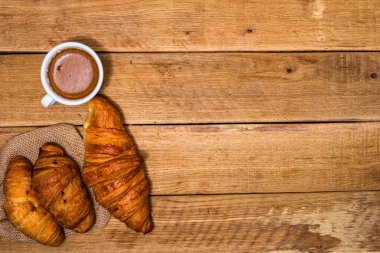 Tahta masada taze kruvasan ve bisküvi. Kahve, yemek ve kahvaltı konsepti. Tatlılar, taze hamur işleri ve kahve. Üst görünüm ve kopyalama alanı