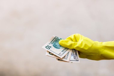 Dünya para kavramı, eldiven alma, 10 dolarlık banknot verme ya da tutma, bulanık arka planda izole edilmiş. Corona virüsü COVID-19 salgını. Virüsün yayılmasını önleme kavramı