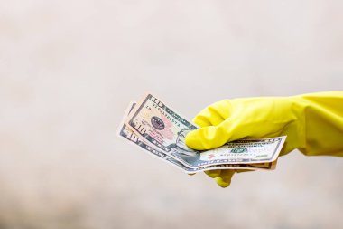 Dünya para kavramı, eldiven alma, 10 dolarlık banknot verme ya da tutma, bulanık arka planda izole edilmiş. Corona virüsü COVID-19 salgını. Virüsün yayılmasını önleme kavramı