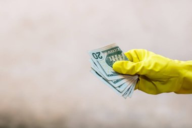 Dünya para kavramı, eldiven alma, 20 dolarlık banknot verme ya da tutma, bulanık arka planda izole edilmiş. Corona virüsü COVID-19 salgını. Virüsün yayılmasını önleme kavramı