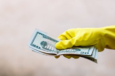 Dünya para kavramı, eldiven alma, 20 dolarlık banknot verme ya da tutma, bulanık arka planda izole edilmiş. Corona virüsü COVID-19 salgını. Virüsün yayılmasını önleme kavramı