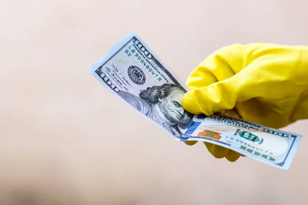 World money concept, hand with gloves receiving, giving or holding 100 USD banknote, isolated on blurred background. Corona virus COVID-19 outbreak. Concept of prevention virus spread