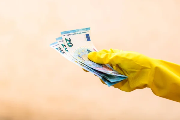 World money concept, hand with gloves receiving, giving or holding 20 EURO banknote, isolated on blurred background. Corona virus COVID-19 outbreak. Concept of prevention virus spread