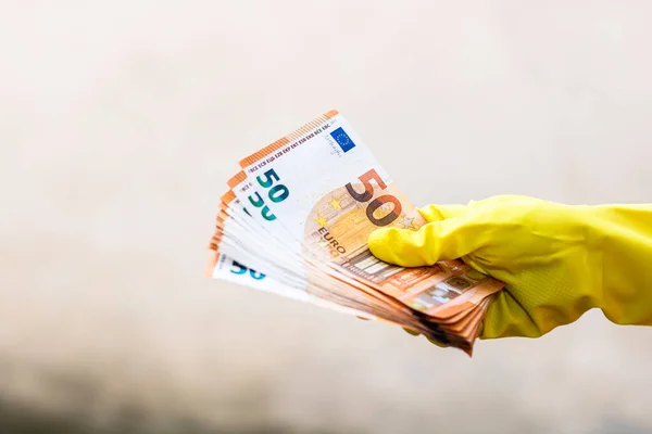 World money concept, hand with gloves receiving, giving or holding 50 EURO banknote, isolated on blurred background. Corona virus COVID-19 outbreak. Concept of prevention virus spread