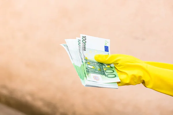 World money concept, hand with gloves receiving, giving or holding 100 EURO banknote, isolated on blurred background. Corona virus COVID-19 outbreak. Concept of prevention virus spread