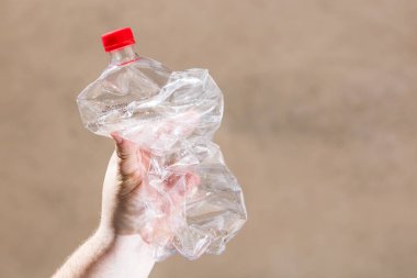 El ele tutuşmak bulanık bir arka planda izole edilmiş boş plastik şişe. Geri dönüşüm ve gönüllü konsepti. Çevre kirliliği ve dünya çapında ekolojik sorun