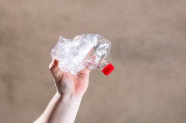 El ele tutuşmak bulanık bir arka planda izole edilmiş boş plastik şişe. Geri dönüşüm ve gönüllü konsepti. Çevre kirliliği ve dünya çapında ekolojik sorun