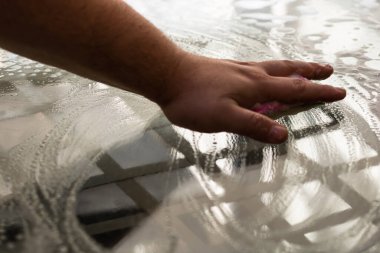 Sünger ve temizlik spreyi kullanarak cam masayı temizleyen adam, temizlik hizmeti konsepti. Ev işleri ve ev idaresi kavramı