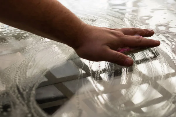 Man cleaning glass table using sponge and cleaning sprayer, cleaning services concept. Housework and housekeeping concept