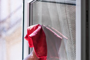 Kırmızı mikrofiber halı kullanarak cam silen bir adam, temizlik hizmeti kavramı. Ev işleri ve ev idaresi kavramı