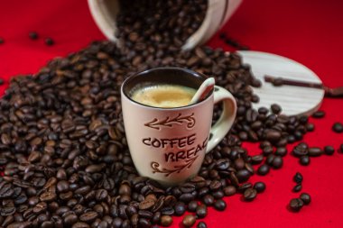 Bir fincan kahve, kırmızı zemin üzerinde kavrulmuş kahve çekirdekleri, üst görünüm, metin için fotokopi alanı, kahve konsepti, kahve fotoğrafını kapat.