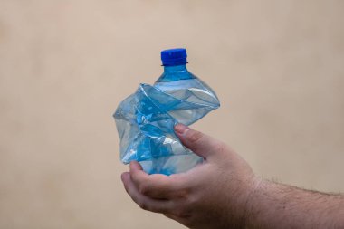 El ele tutuşmak bulanık bir arka planda izole edilmiş boş plastik şişe. Geri dönüşüm ve gönüllü konsepti. Çevre kirliliği ve dünya çapında ekolojik sorun